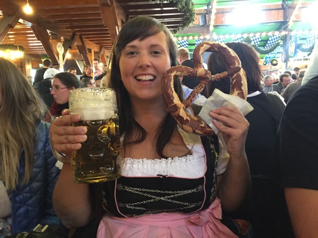 Cailin looking the part at Oktoberfest with a real traditional dirndle dress, liter beer and pretzel - Where to buy a dirndl dress and lederhosen pants for Oktoberfest